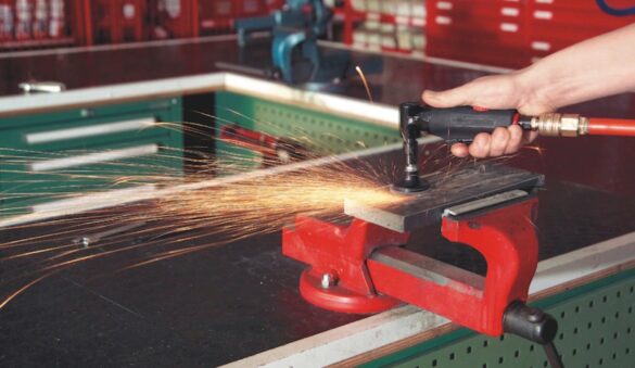 Ponçage d’une pièce métallique avec une ponceuse pneumatique dans un atelier professionnel – projection d’étincelles, outil à air comprimé Würth.